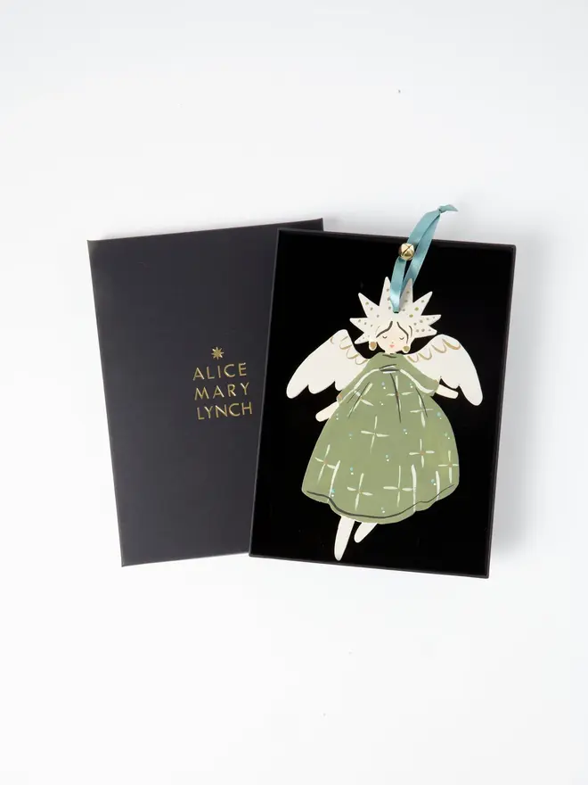 Angel Tree Dancer. wooden hanging angel decoration in an open black gift box embossed "alice mary lynch" in gold, with a star-shaped gold-flecked halo, cream wings and sage green star-patterned gown, duck egg blue ribbon with a jingle bell