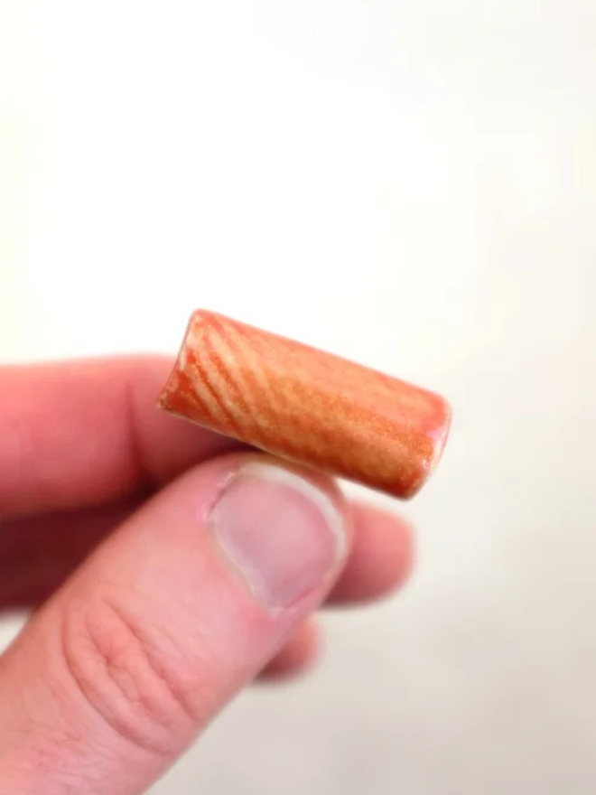 ceramic pasta pin badges. a ceramic rigatoni badge photographed up close.