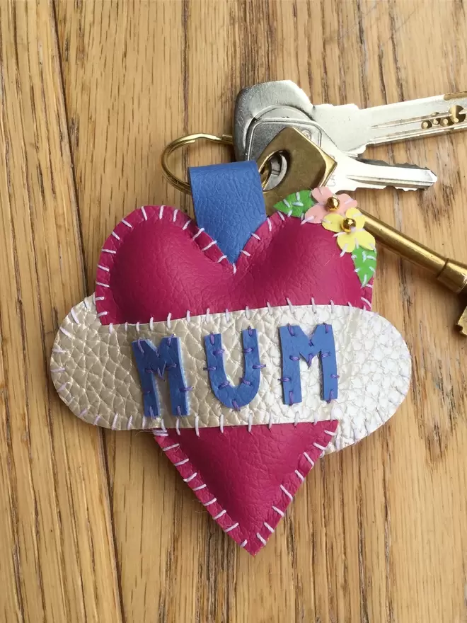 Pink heart keyring, with MUM stitched in blue lettering, and tiny yellow and pink flower detail