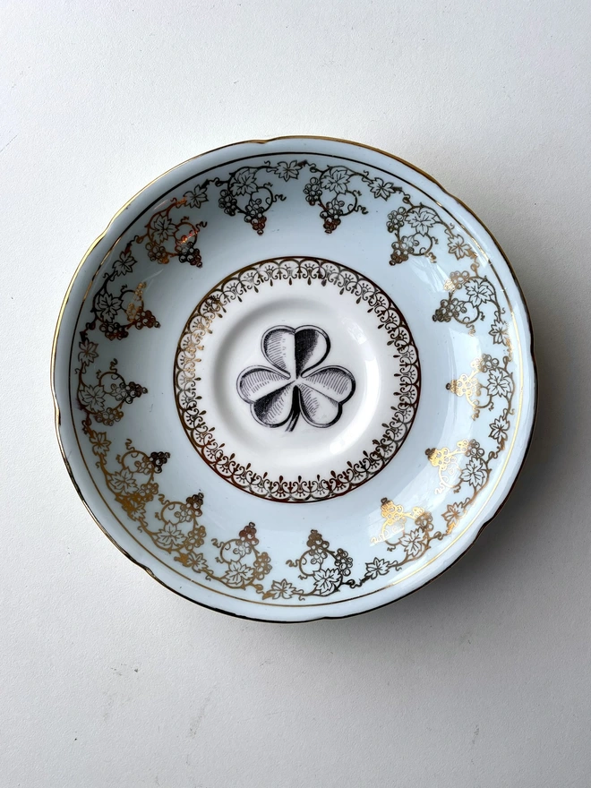 vintage plate with ornate border has a black and white image of a victorian lucky irish shamrock in the centre