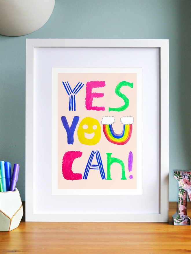 Art print saying 'Yes you can' in a white frame in a child's room