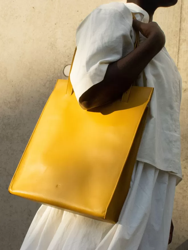 Close up of Amber Yellow Tote Bag worn over the shoulder on a beautiful darker complexion model