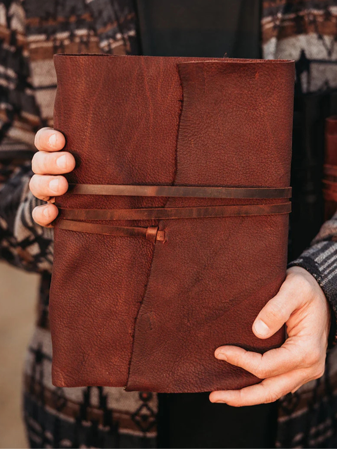 reclaimed saddlery leather journal. a brown leather journal held in foreground.
