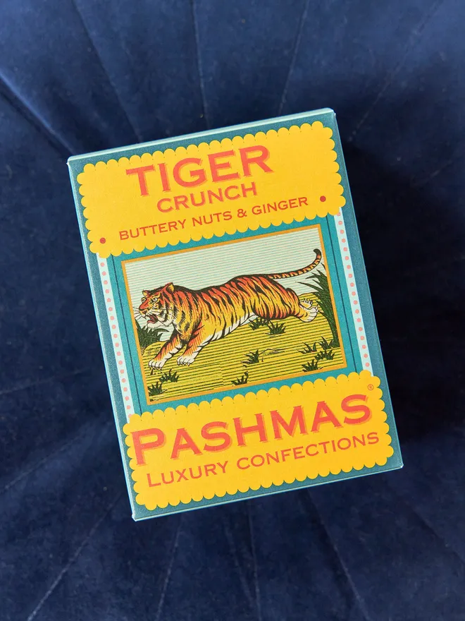box of tiger crunch mithai sweets on blue cushion