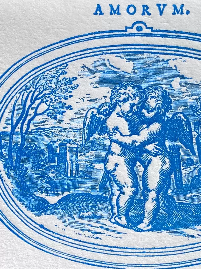 Close up of white card with blue illustration of cherubs