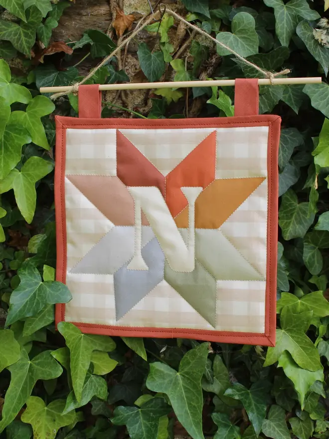personalised initial quilt hanging. a hand-sewn hanging quilt with a star design in the centre, alongside the initial 'N'.