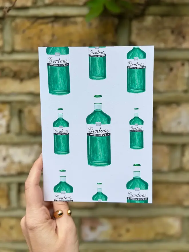 gin bottles illustrated card. card photographed against brick wall backdrop.