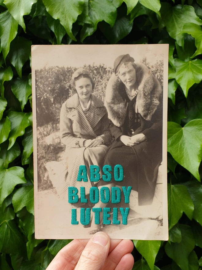 B&W photo of 2 women with Abso-bloody-lutely in teal embroidered across, original photo