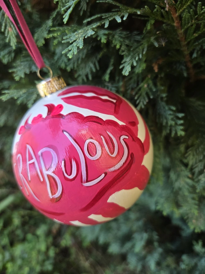 Hand painted bauble hanging from a christmas tree, with crab design and Crapulous slogan