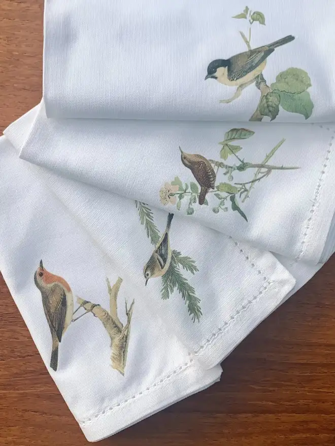 a set of four white cotton napkins with birds