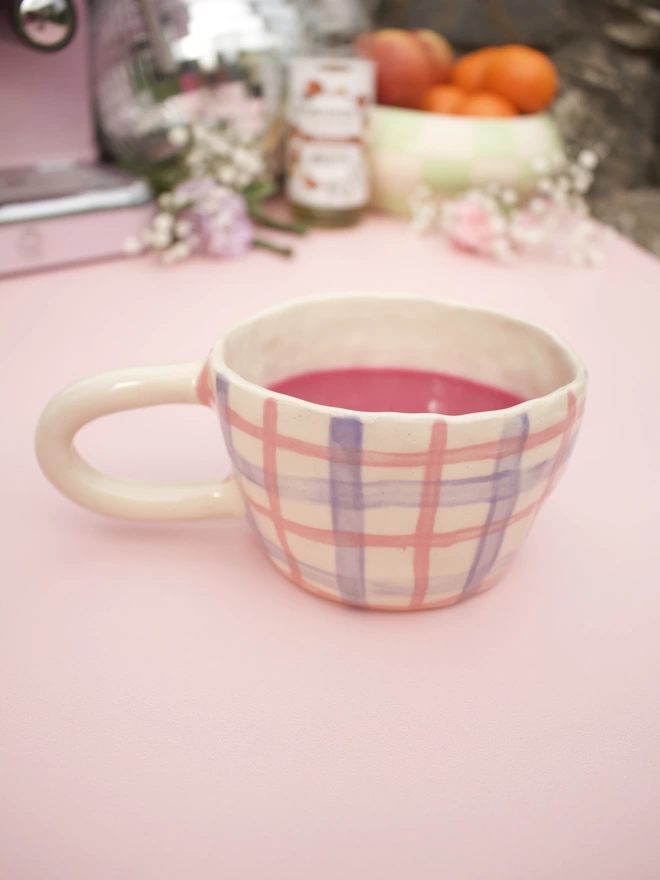 pink and purple gingham striped patterned stoneware pottery mug with bright pink drink inside