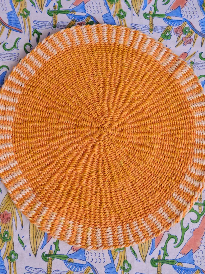 Yellow placemat sitting on a colourful tablecloth