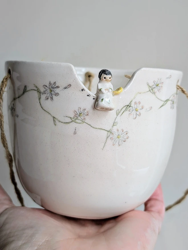 Pottery planter plant pot with a tiny angel sitting on the rim and hand painted daisy chain