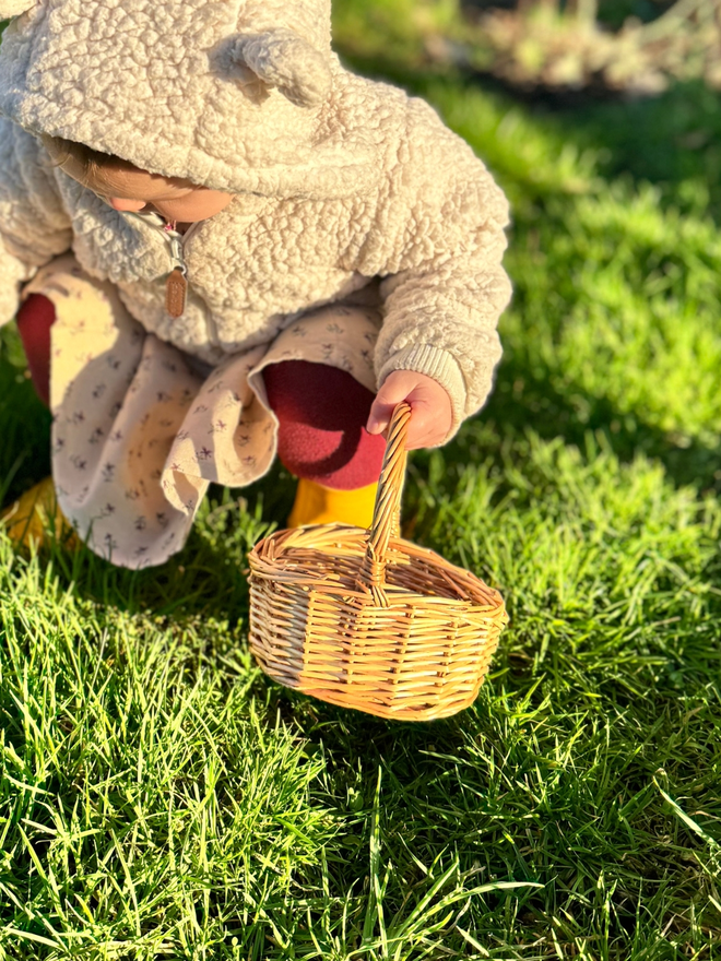 Child crouching holding wicker basket