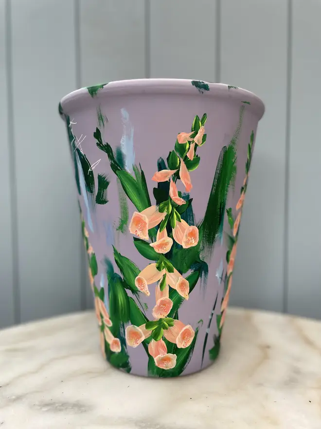 Unique hand-painted terracotta pot featuring apricot foxgloves on a lilic background