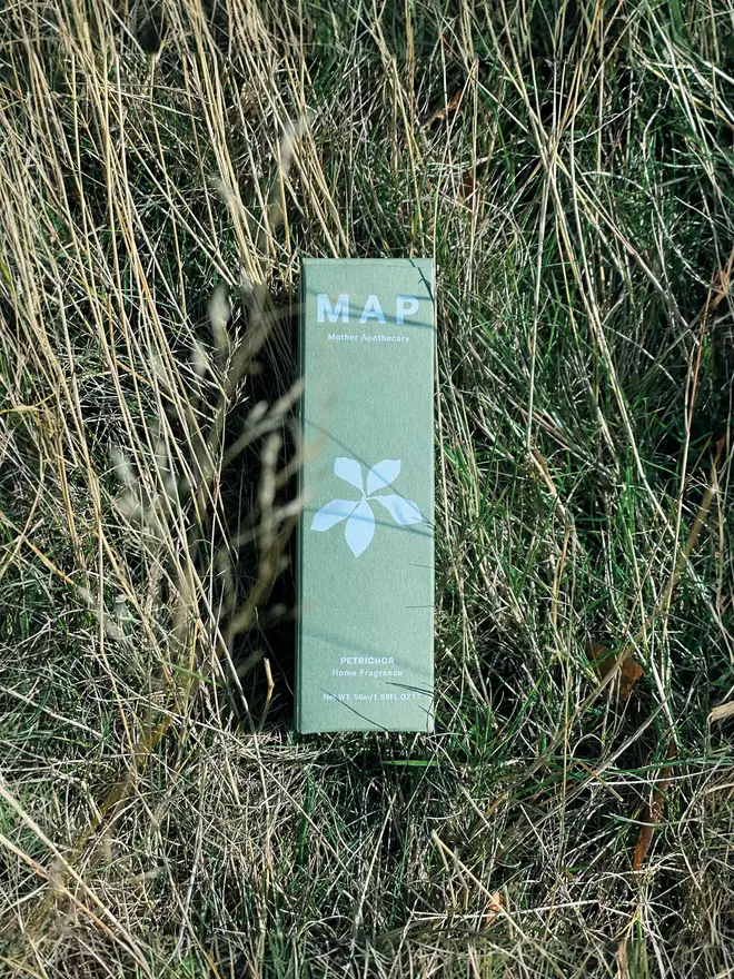 petrichor earthy home fragrance spray. packaging box photographed in grass.