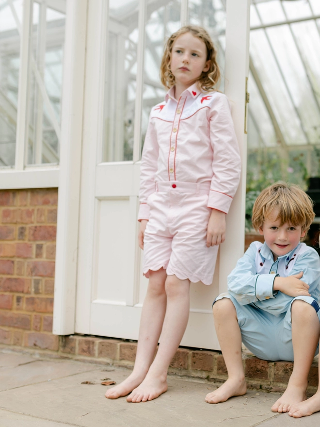 Two children wearing cowboy shirts. The girl's is pink with heart and swallow embroidery