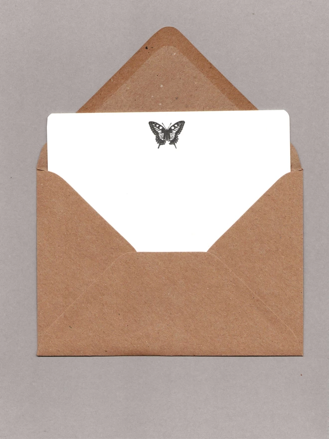 White notecard with a black butterfly at the top inside an open kraft envelope