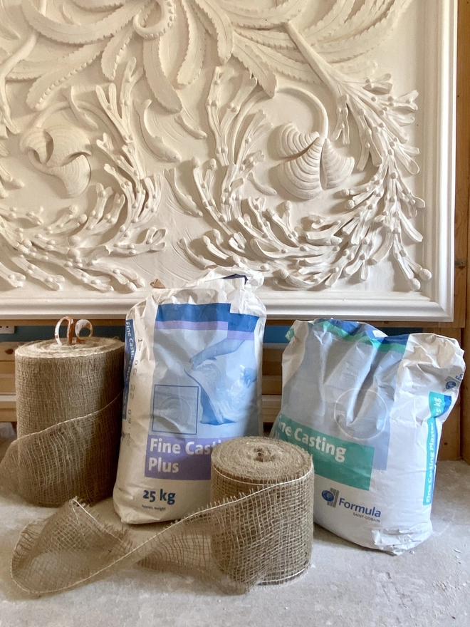 Bags of casting plaster and hessian scrim in front of decorative plaster wall sculpture