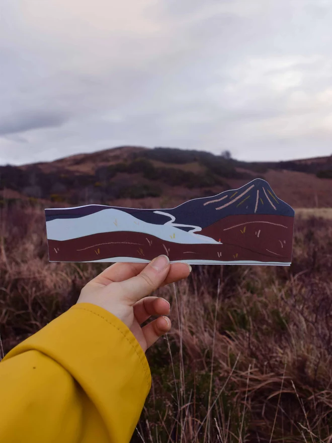 Cut out card of a mountain with a mountainous landscape in the background of the image. 