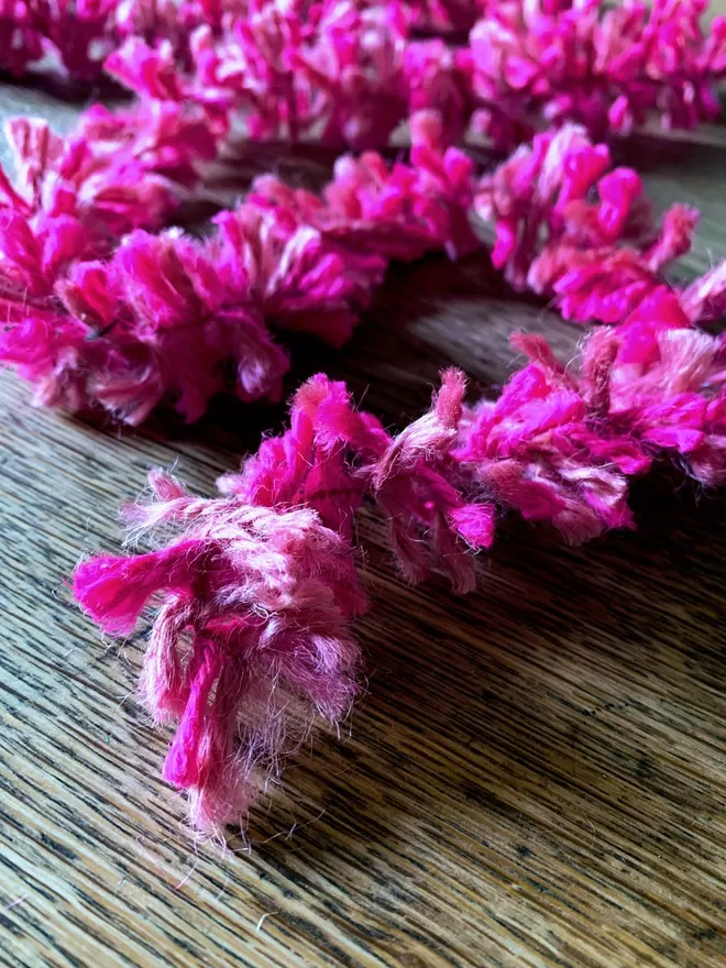 Close up of bright pink jute string tinsel AKA Strinsel on an oak table