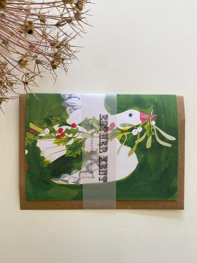Esther Kent illustrated Christmas Card showing white goose on green inky background, carrying holly and mistletoe