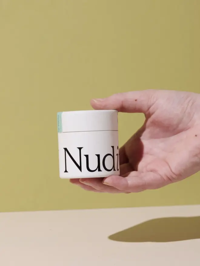 hand holding white tub of matcha