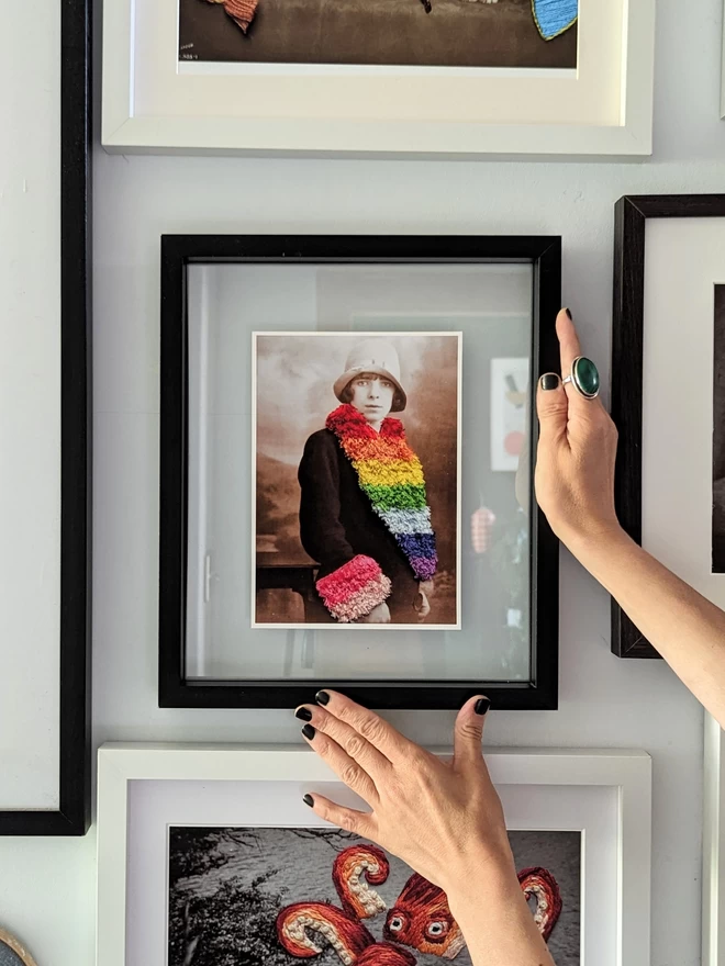  Print of woman wearing embroidered rainbow coloured trim coat framed held against wall