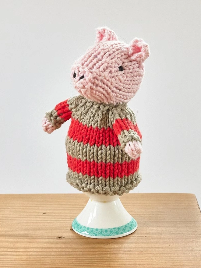 Egg Cosy Pigs Table Decoration (Set Of 2), a colourful pig cosy sitting on a wooden surface. 
