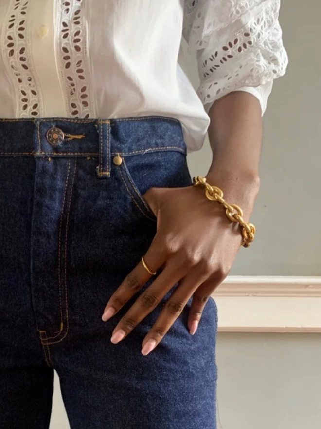 a model wearing dark blue jeans teamed with a contemporary modern chain bracelet