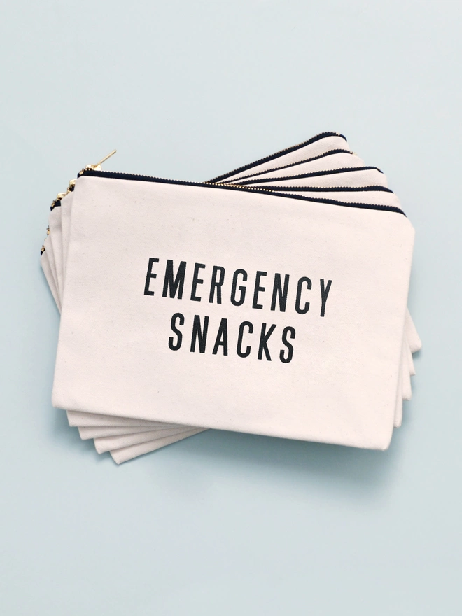 a pile of natural canvas zip pouches with the words emergency snacks