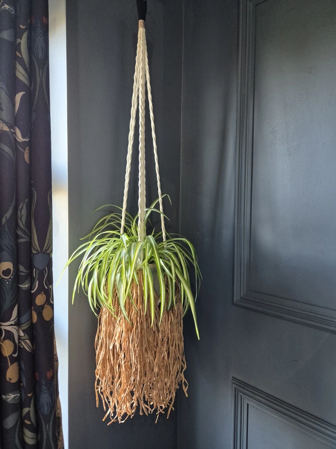 Handmade boho raffia paper plant hanger, adding texture and warmth to any space with a unique raffia fringe. stylish and modern hanging planter, perfect for indoor greenery and home decor trends