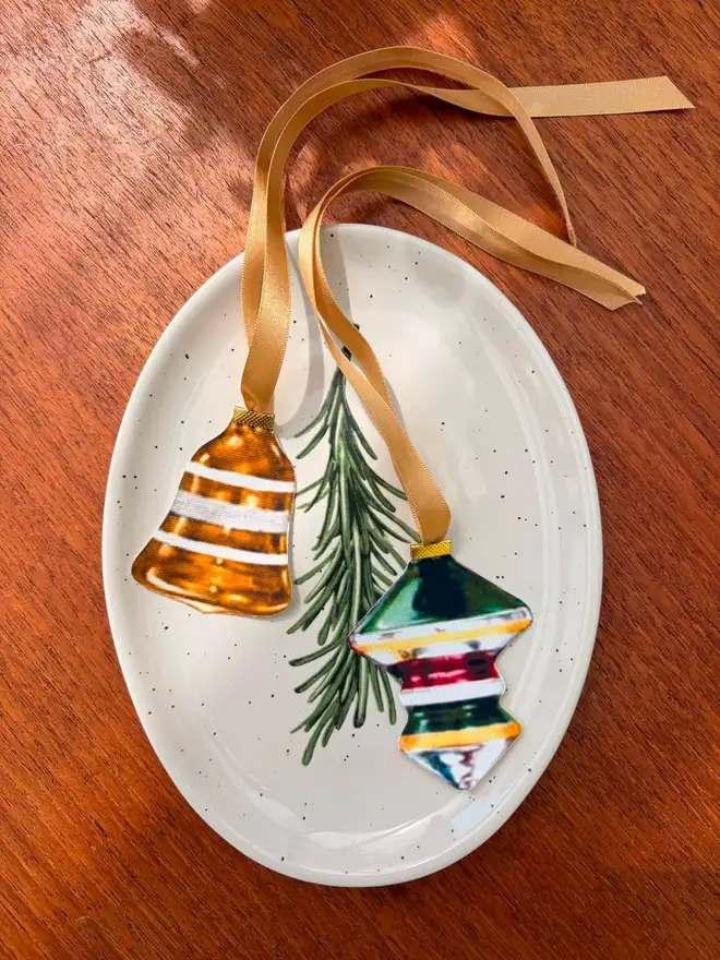 Two vintage bauble shaped napkin ties with gold ribbon on an oval ceramic plate