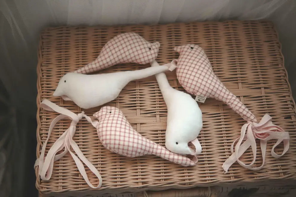 Cotton Bird Garland Decoration, a red and white cotton bird garland sitting on a wooden hamper. 