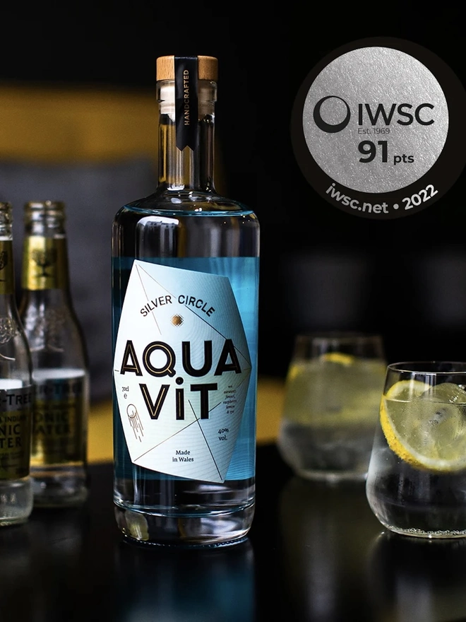 Silver Circle Aquavit, bottle of spirit next to glasses on a table. 