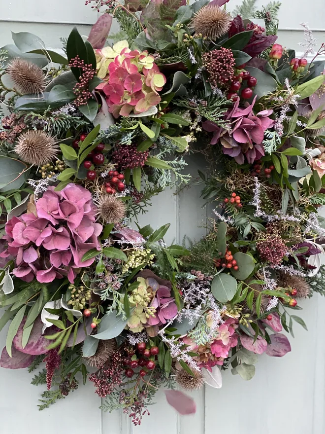 Floral wild hydrangea door wreath. a wreath hung on a white door made up of foliage and wild hydrangea flowers.
