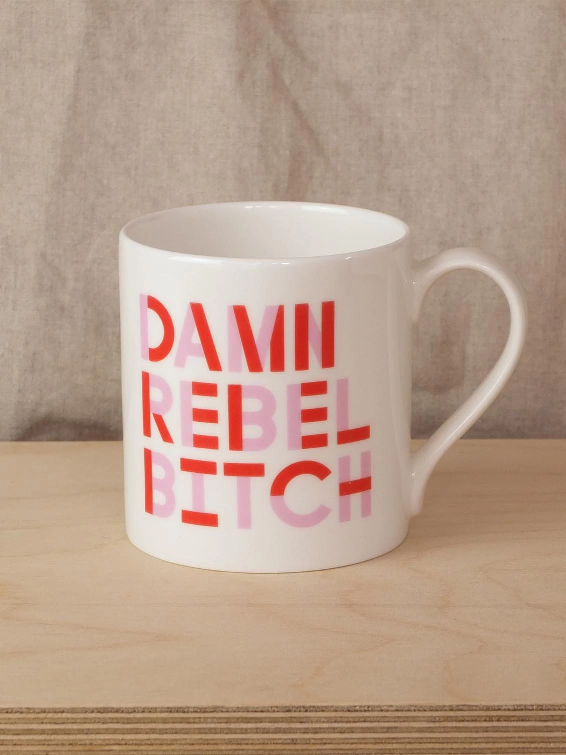 Black & Beech white mug with Damn Rebel Bitch written on both sides in Pink and Red 