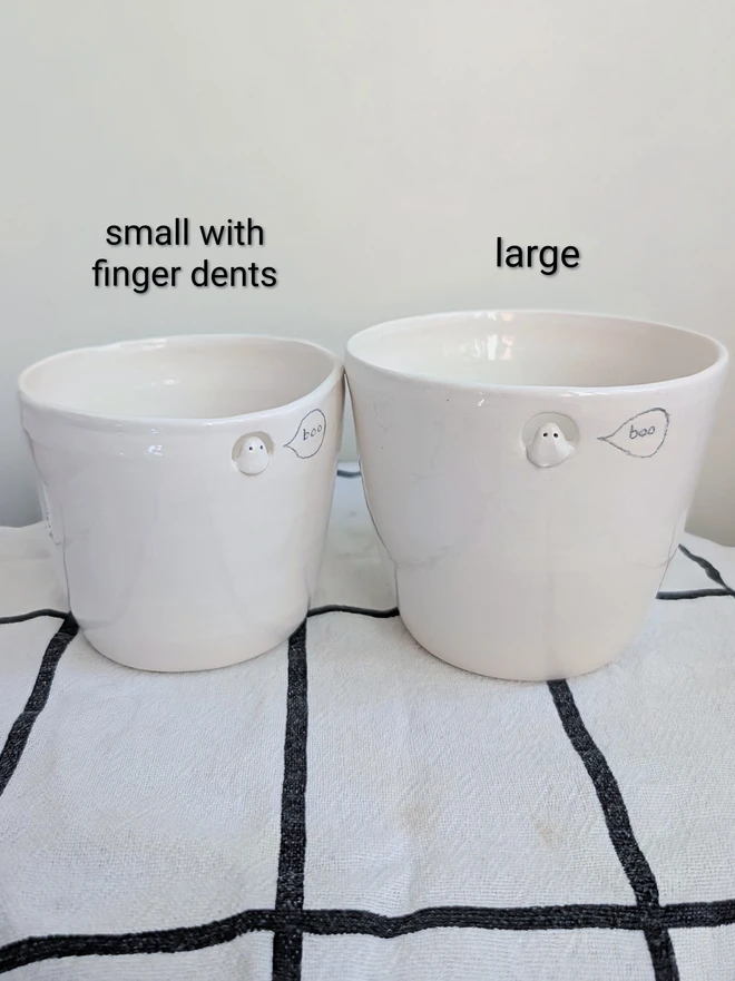 Small and large ghost cups in white handmade ceramic with a tiny sculpted ghost in a cut out near the top of the beakers with a hand painted bubble with the word boo. Beaker for halloween 