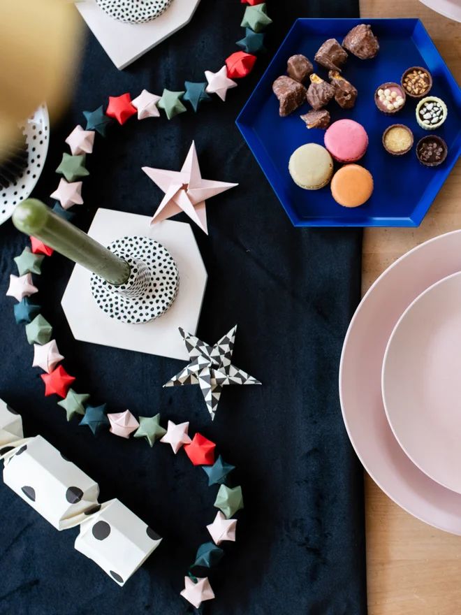 A table decorated for Christmas, with snacks, origami stars, paper crackers and place setting