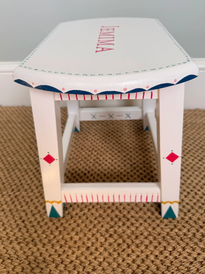Jemima Personalised Hand Painted Stool. A white stool with intricate red and blue designs and personalisation.