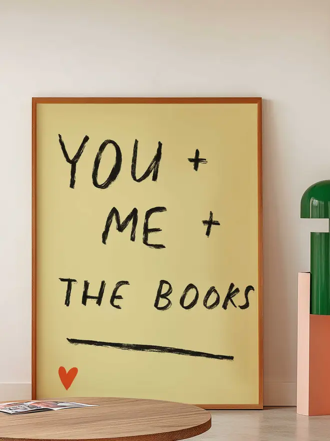 Print in frame leaning against wall reads "You and me and the books"