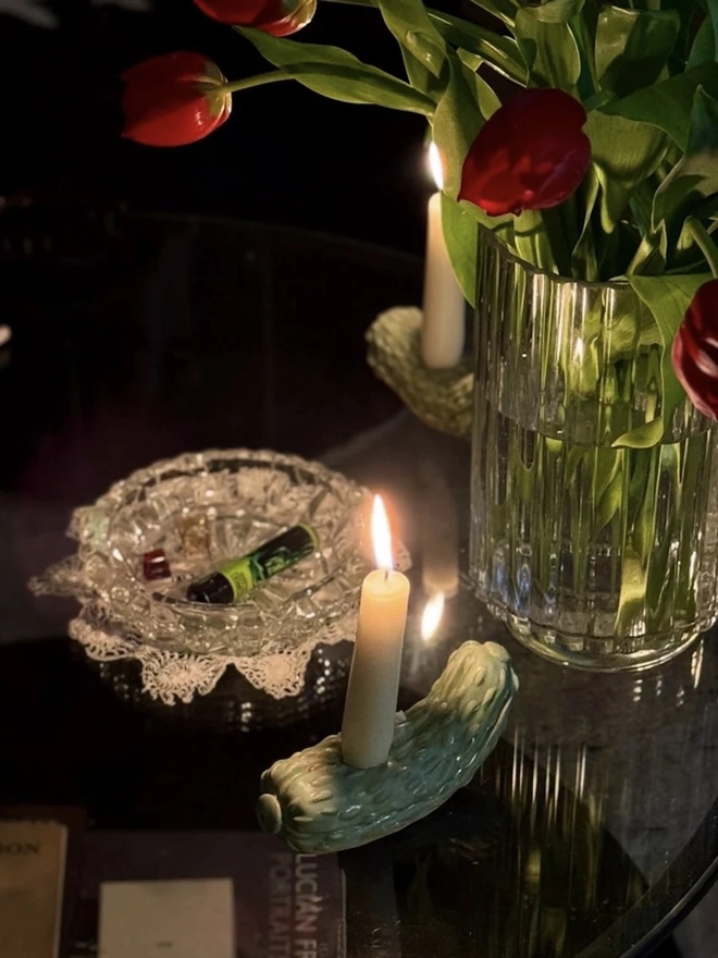 Pickle Candle Holder, a pickle candle holder sitting on a glass surface with a candle in it. 