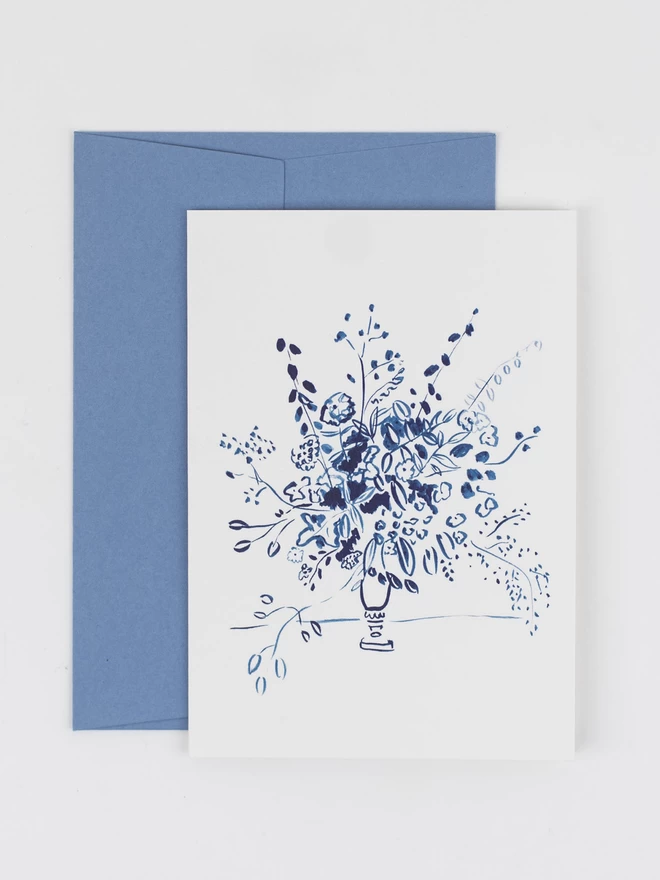 A greetings card featuring a delicate illustration of a bouquet, painting in one colour of navy blue ink. The card is photographed with it's corresponding pale blue envelope.