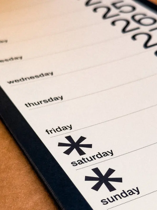 Closeup of Obok 2027 Arched Wall Calendar showing two asterisks highlighting weekends.