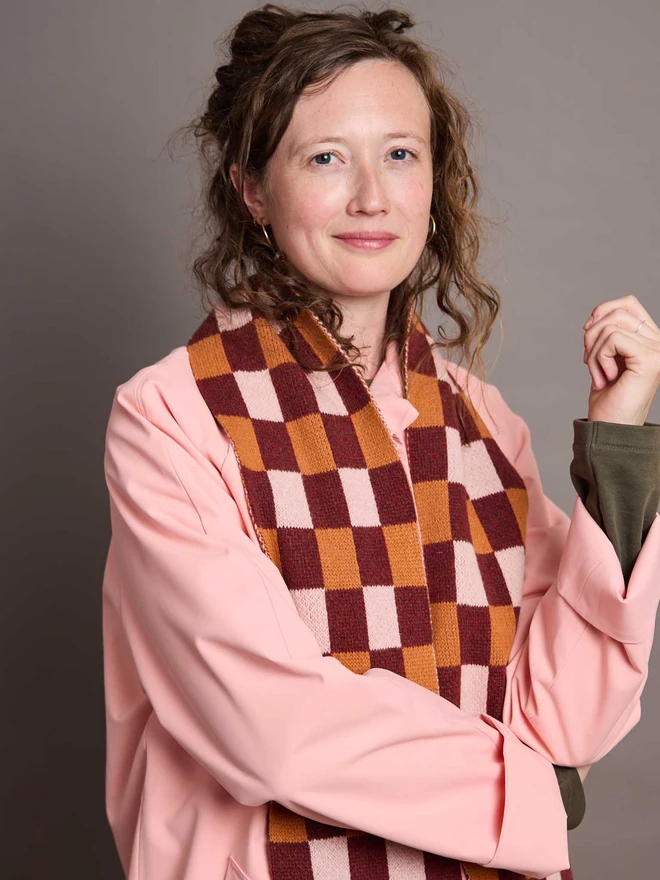 Dark Red And Rust Patterned Wool Scarf Modelled By A Woman In A Pink Coat