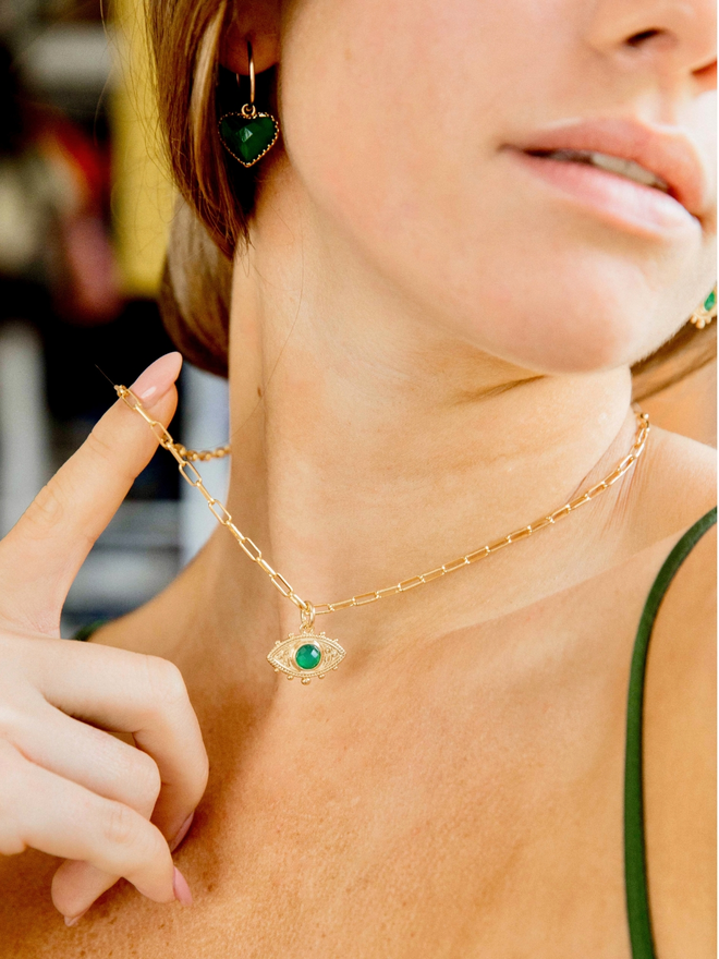 Woman wearing green evil eye charm on gold paperclip chain