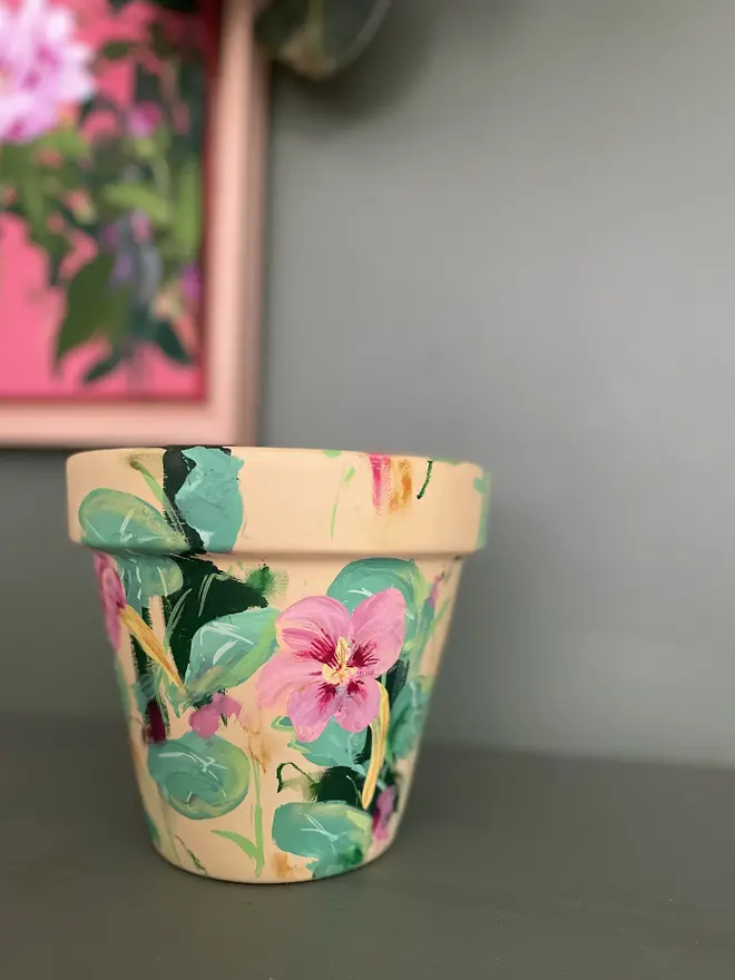 A beautifully hand painted interior terracotta plant pot. Background painted in a pastel yellow adorned in pale rose nasturtium flowers.