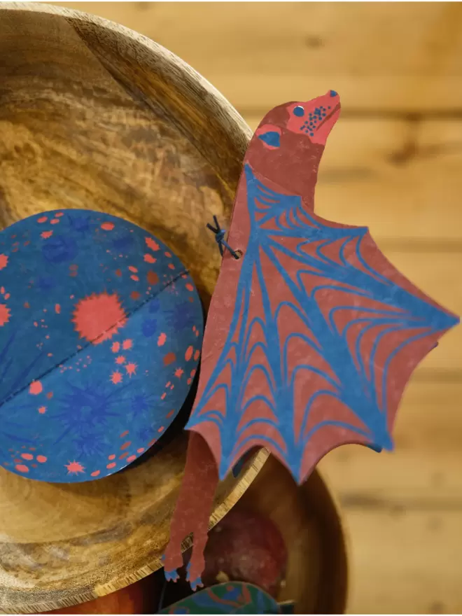 Close-up, detailed shot: red and blue bat along side the blue moon 