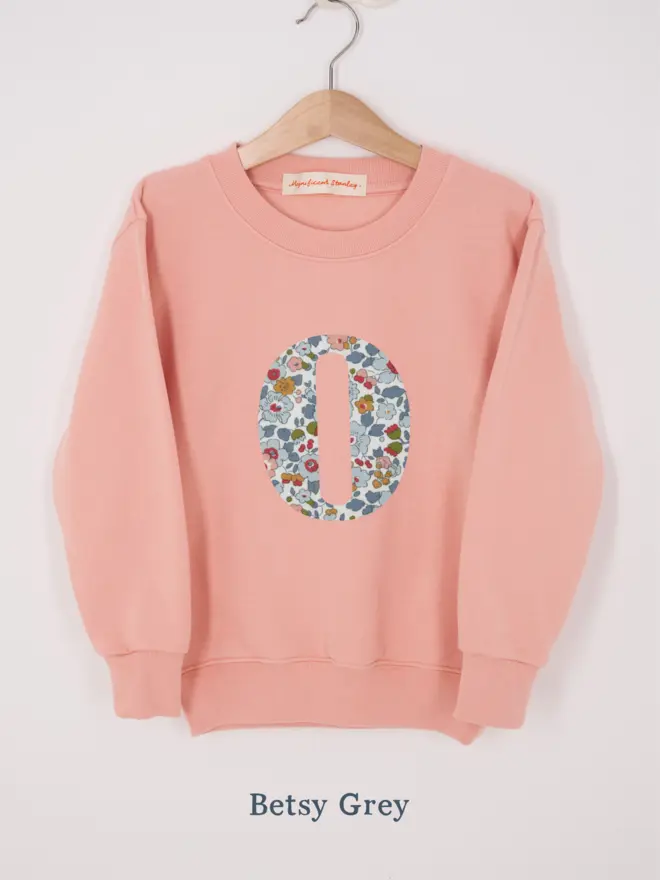 a personalised dusty pink sweatshirt with her initial sewn on the front in space liberty print 