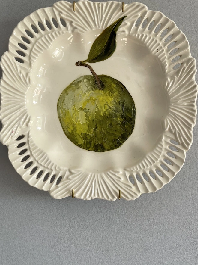painted green apple on reticulated plate